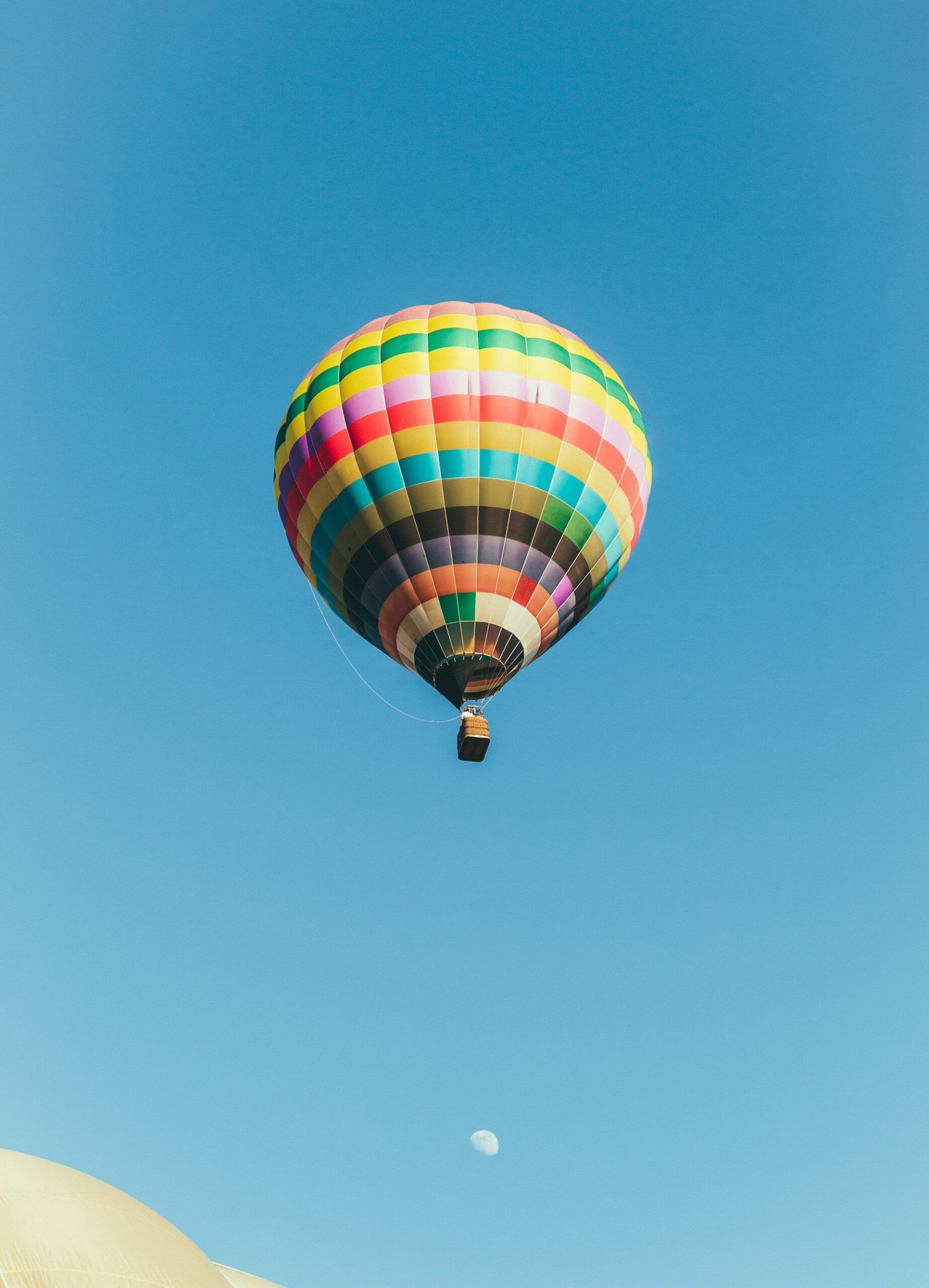 A colorful hot air balloon is flying in a clear blue sky.