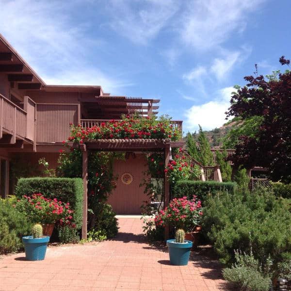 A brick walkway leading to a house with flowers in pots