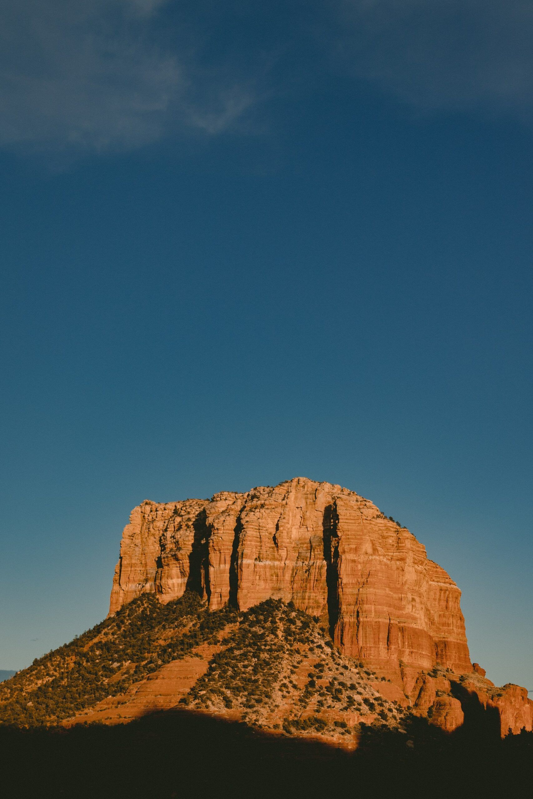 A large rocky mountain with a blue sky in the background.