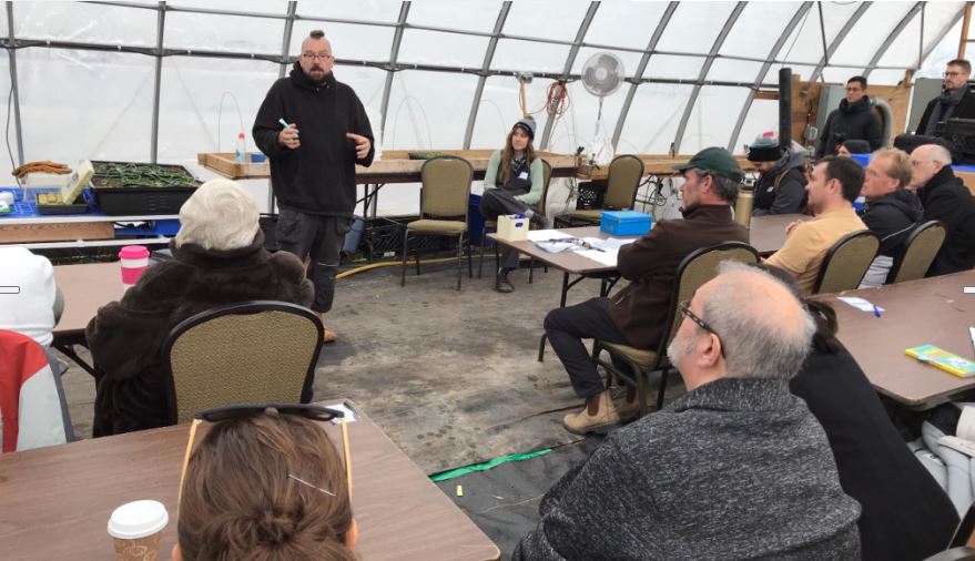 workshop taking place in a greenhouse about hydroponic growing systems