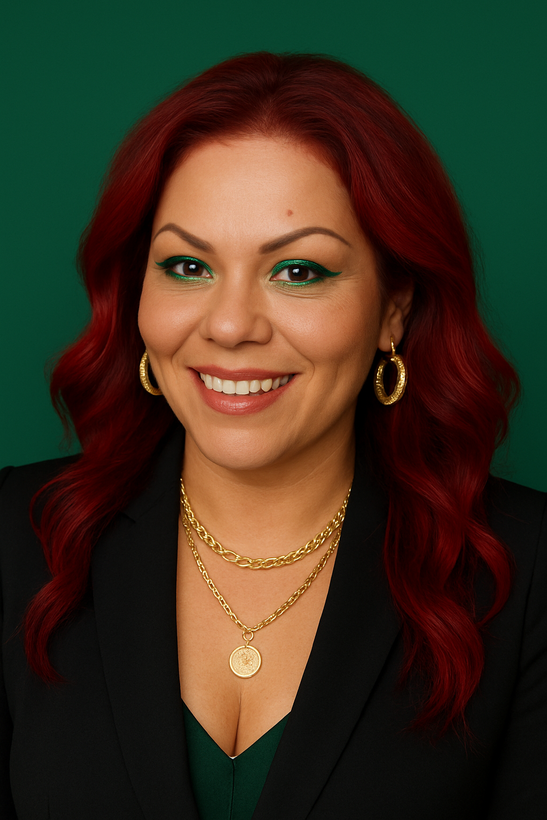 A woman is sitting at a desk with a laptop and a vase of flowers.