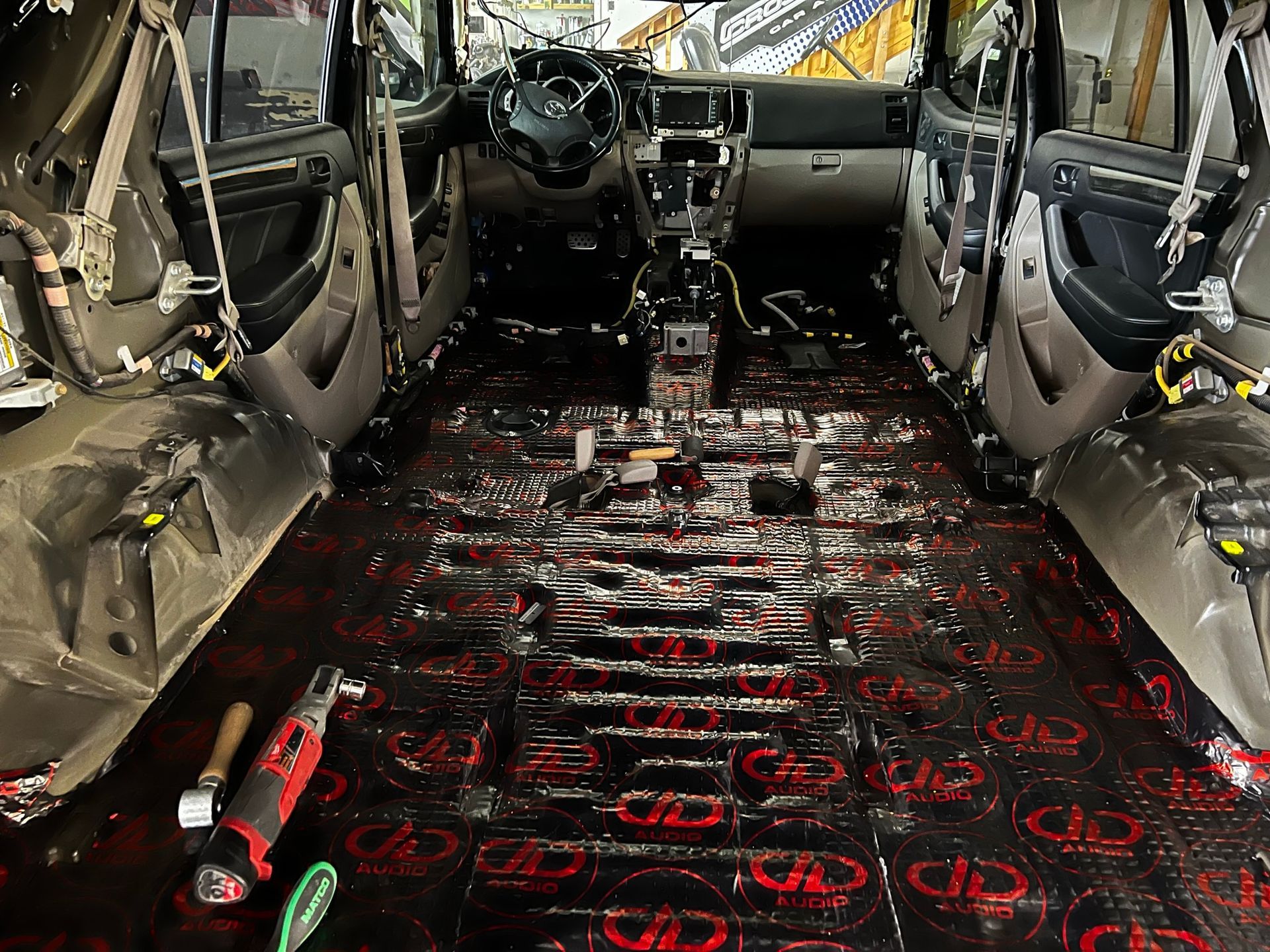 The inside of a car is being worked on with a lot of tools on the floor.