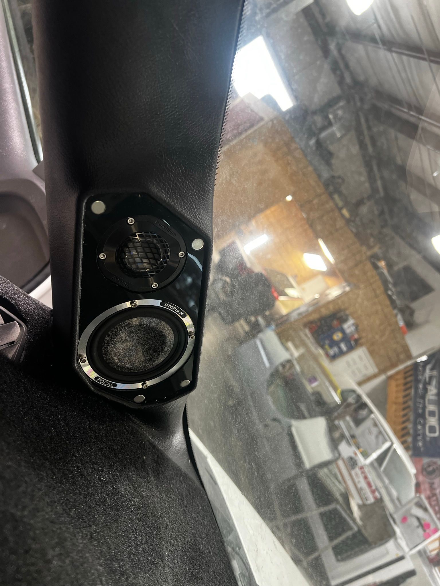 A close up of a speaker on the side of a car in a garage.