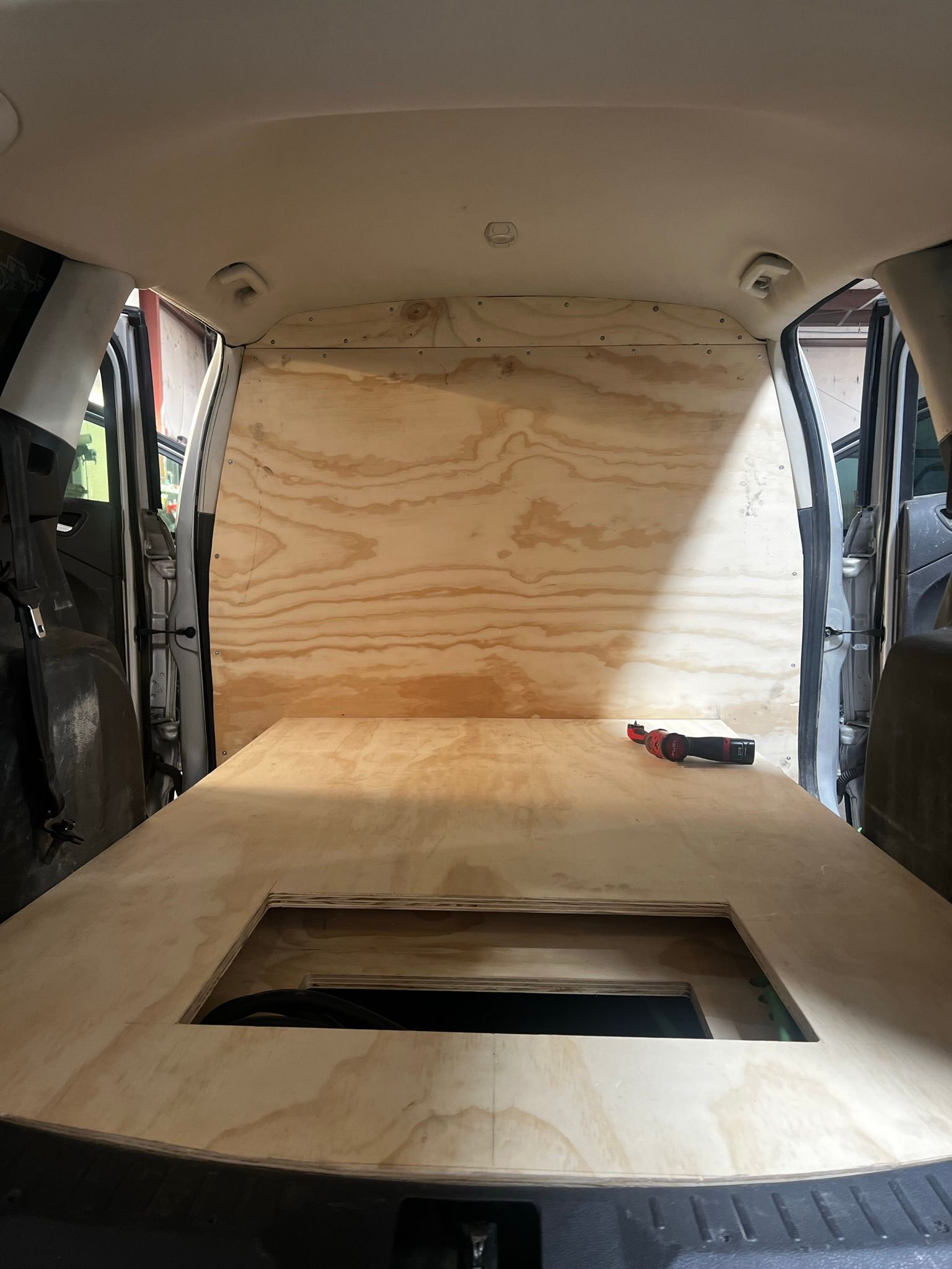 The inside of a van with a wooden floor and a hole in the floor.