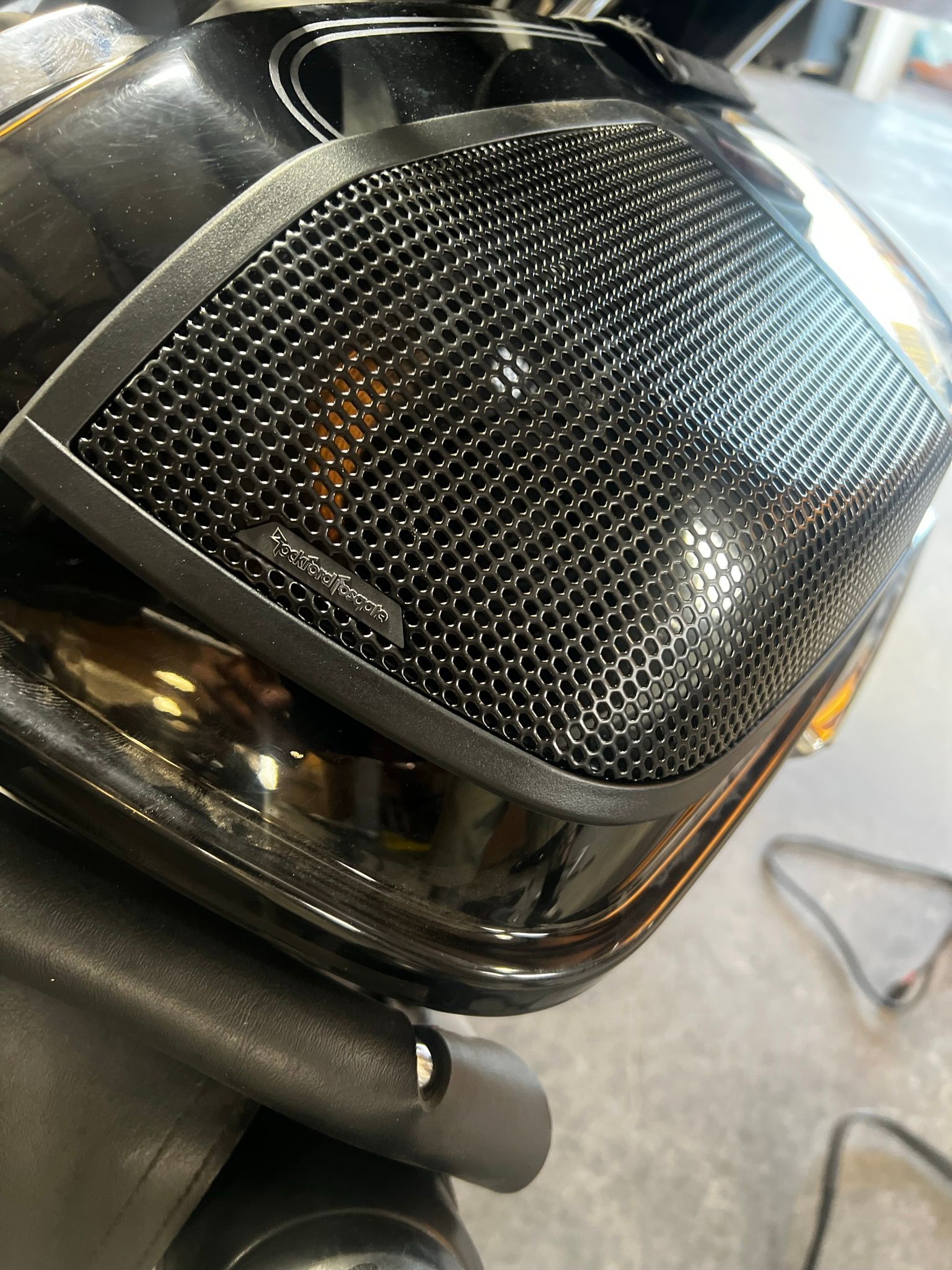 A close up of a motorcycle headlight with a mesh cover on it.