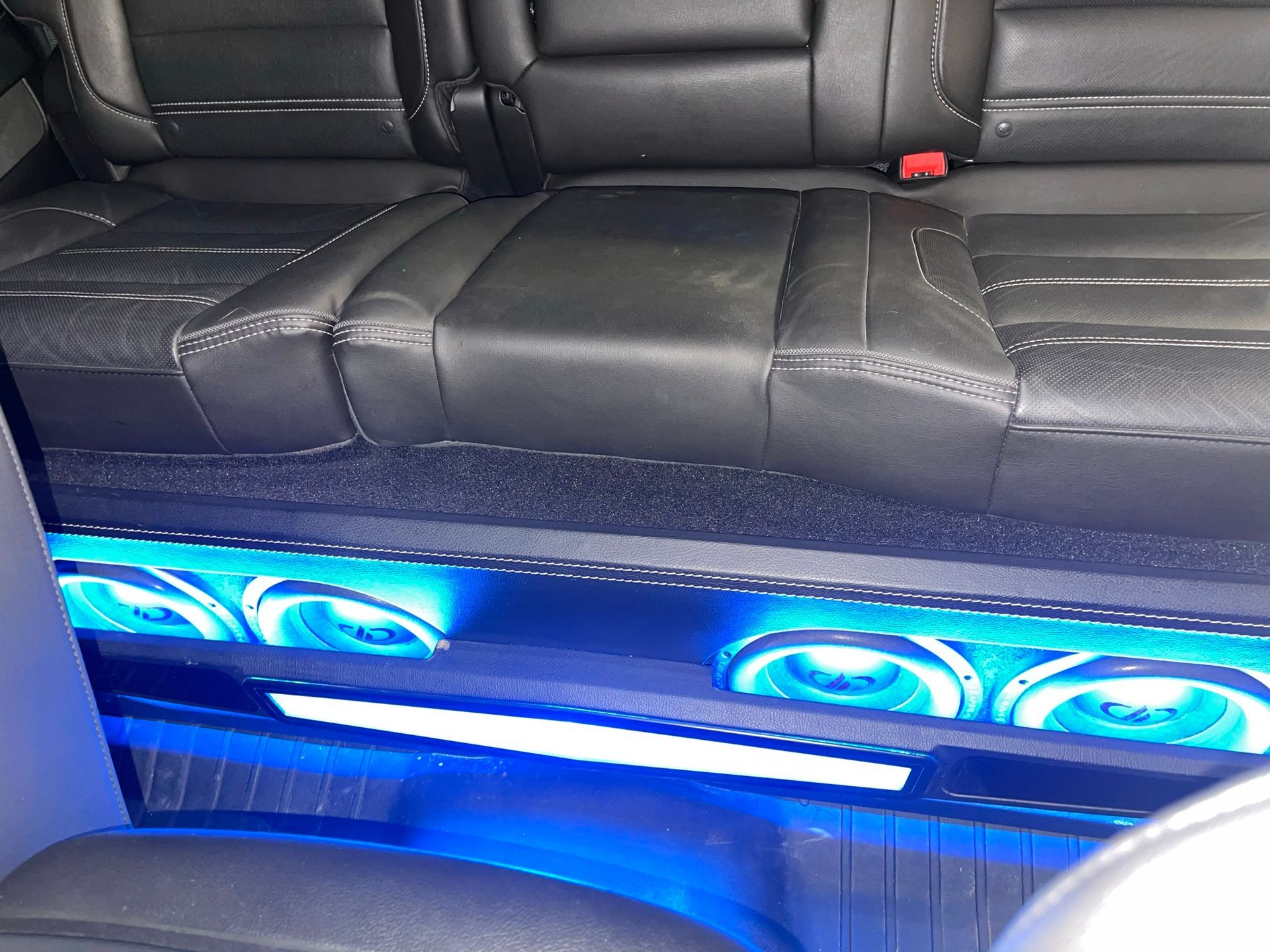 The back seat of a car with blue lights on the floor.