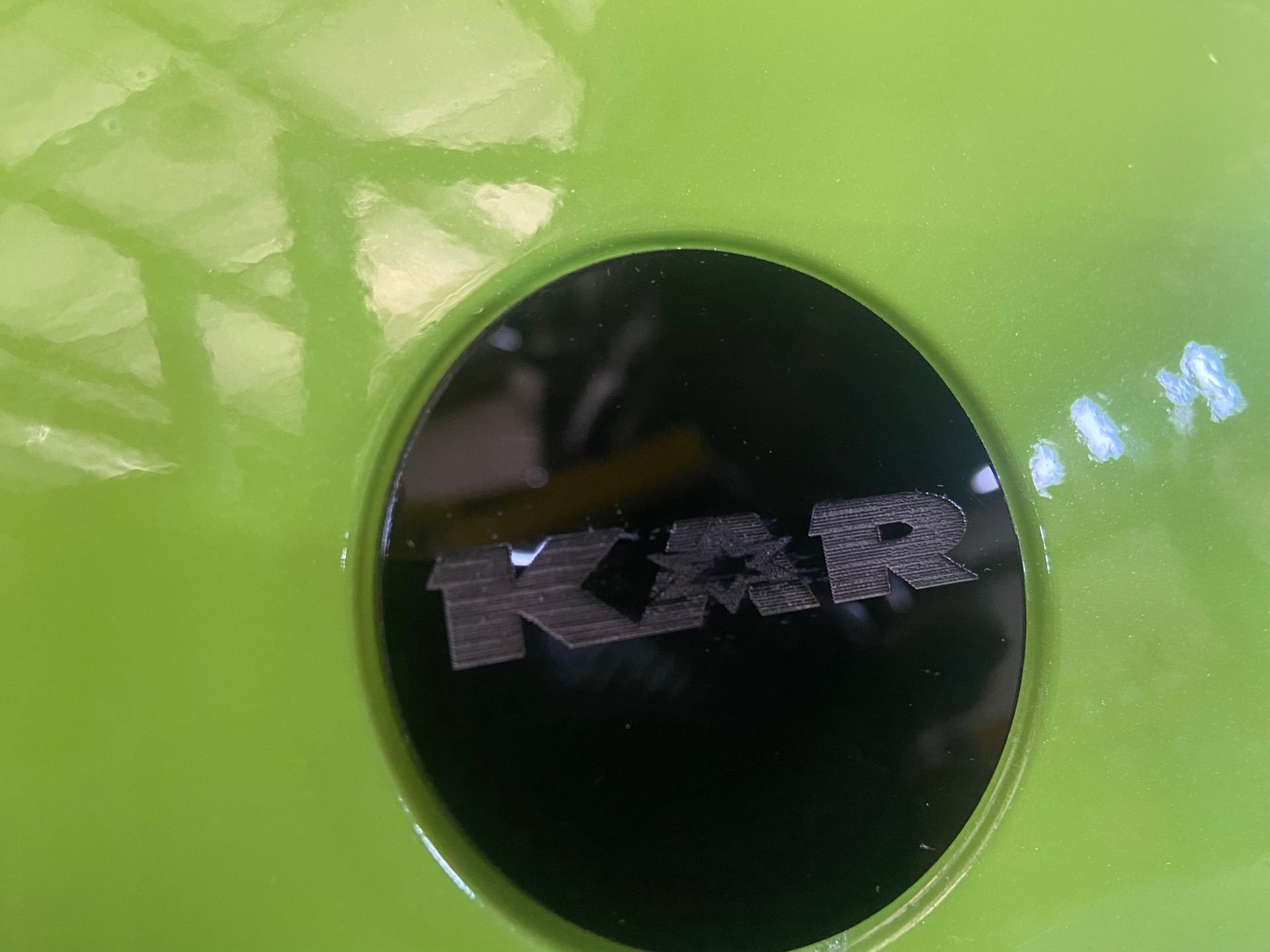 A close up of a green car with a black logo on it.