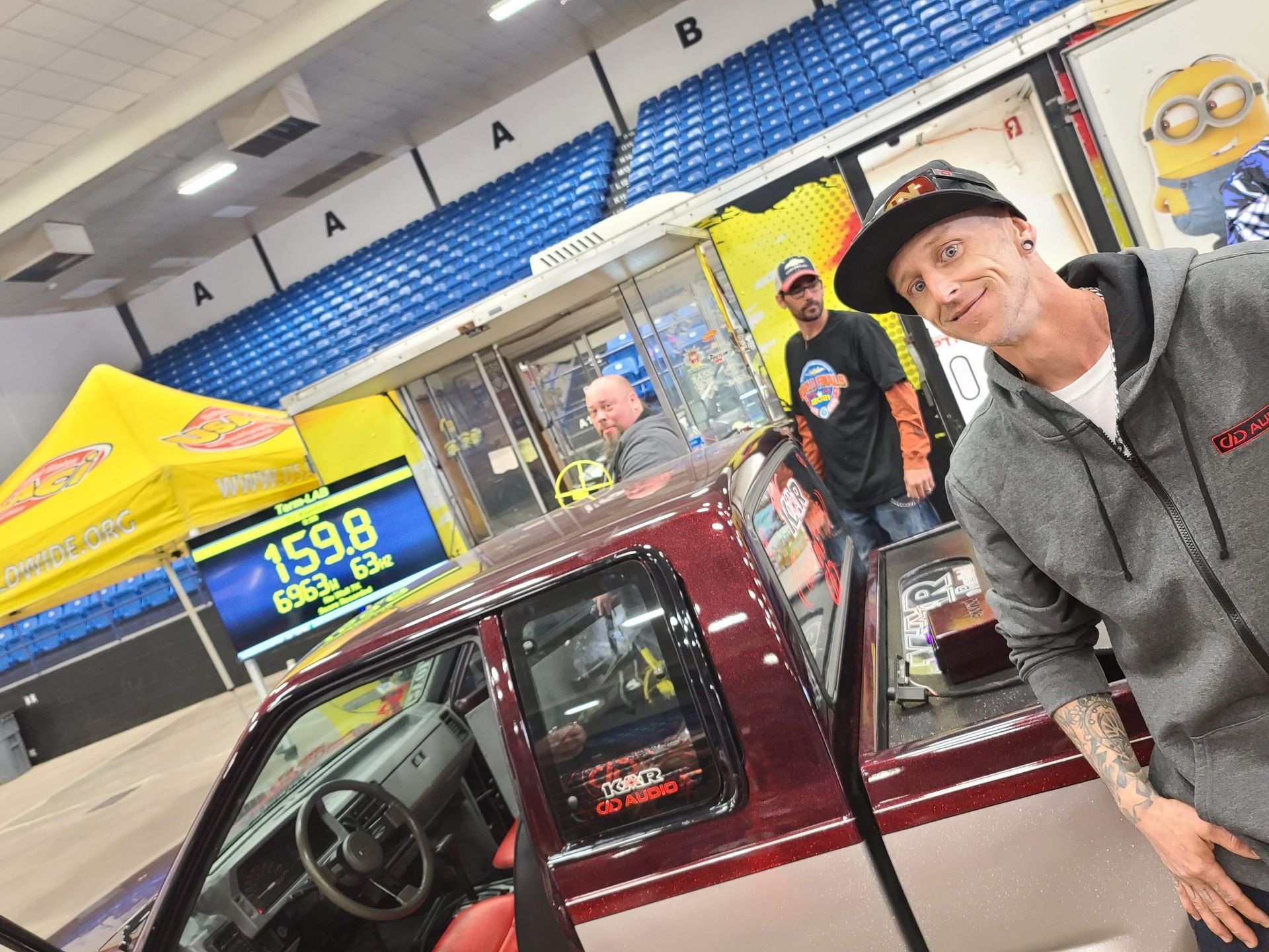 A man is standing in front of a red truck with a sign that says 159.8