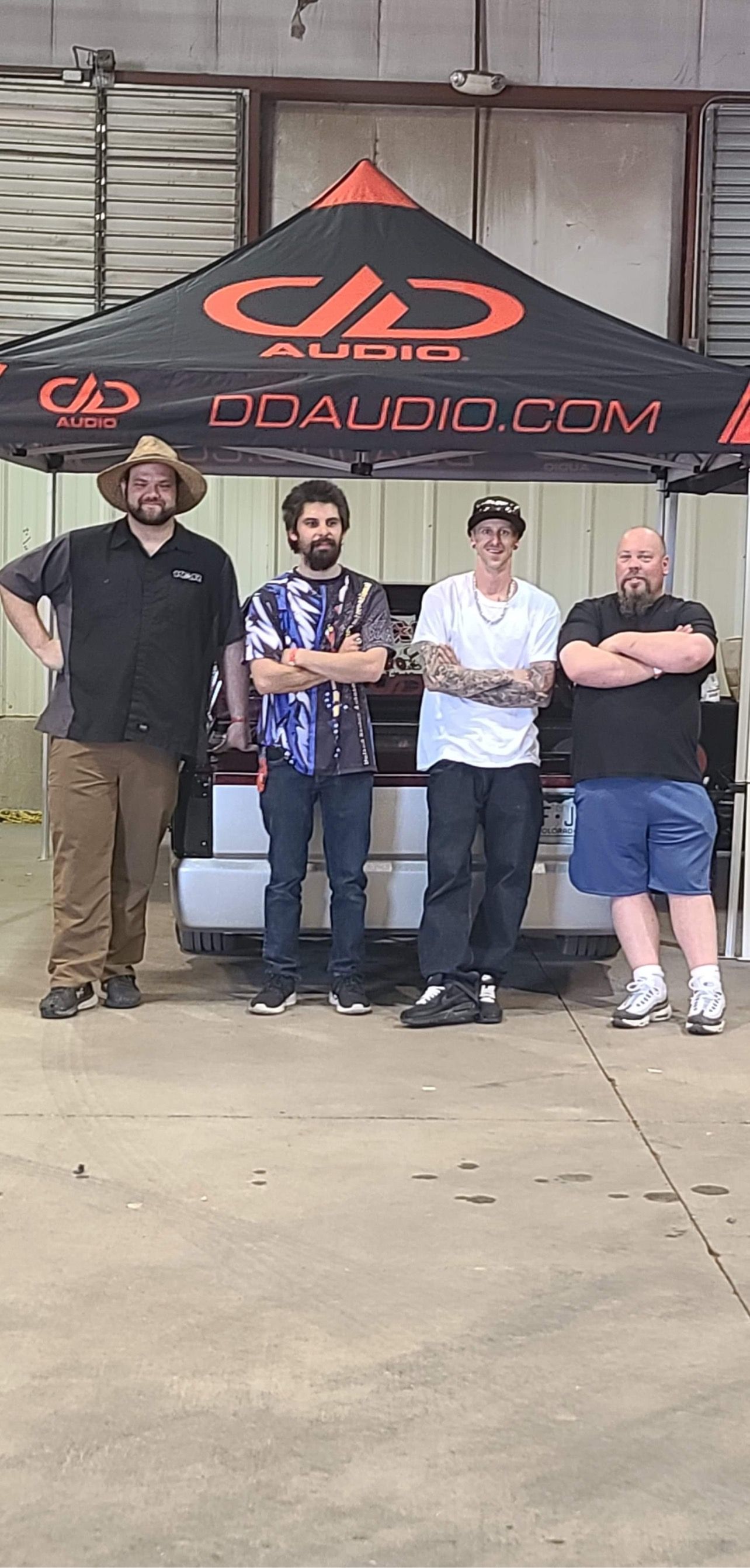 A group of men are standing under a tent in front of a building.