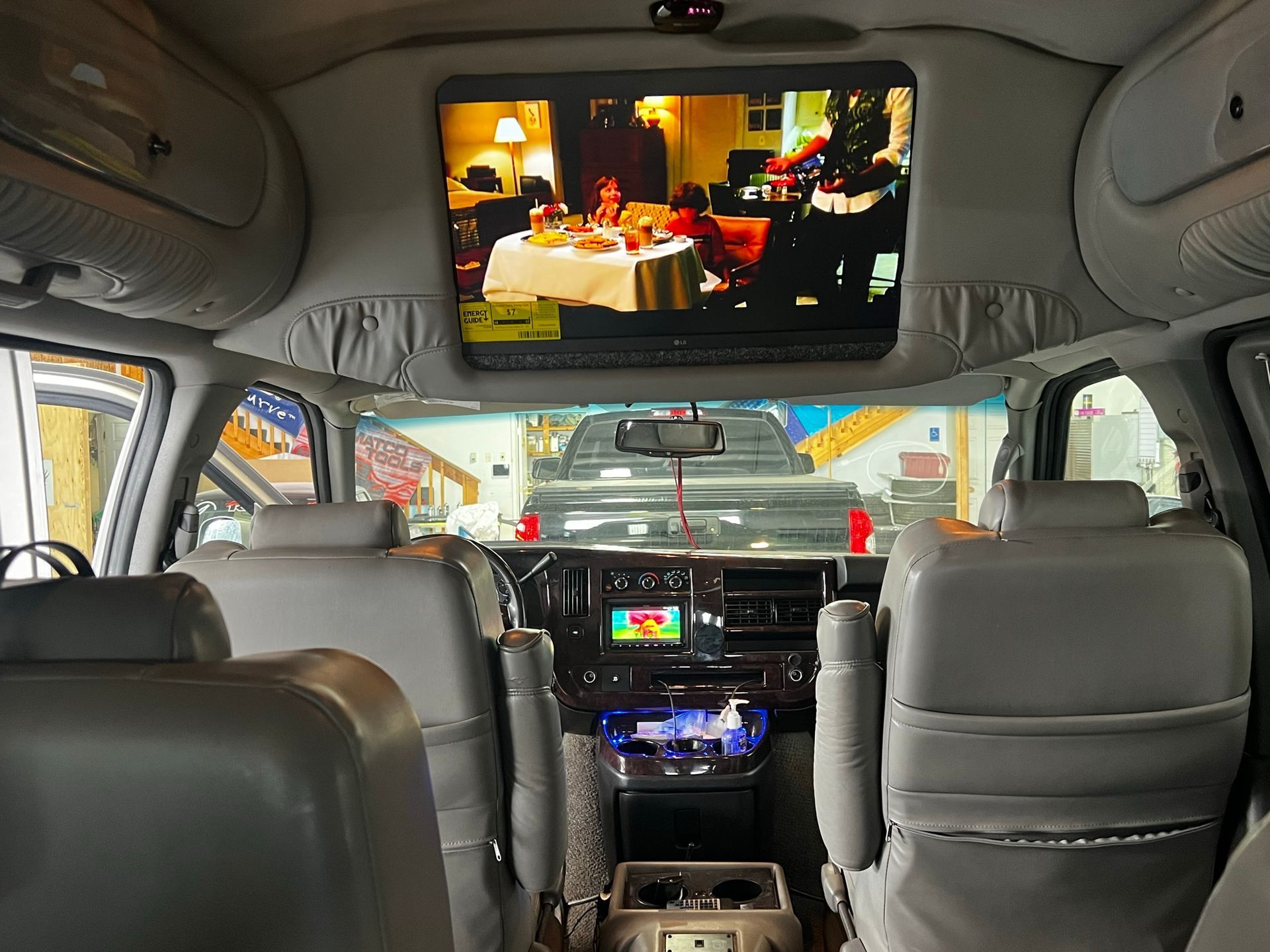 The inside of a van with a flat screen tv above the dashboard