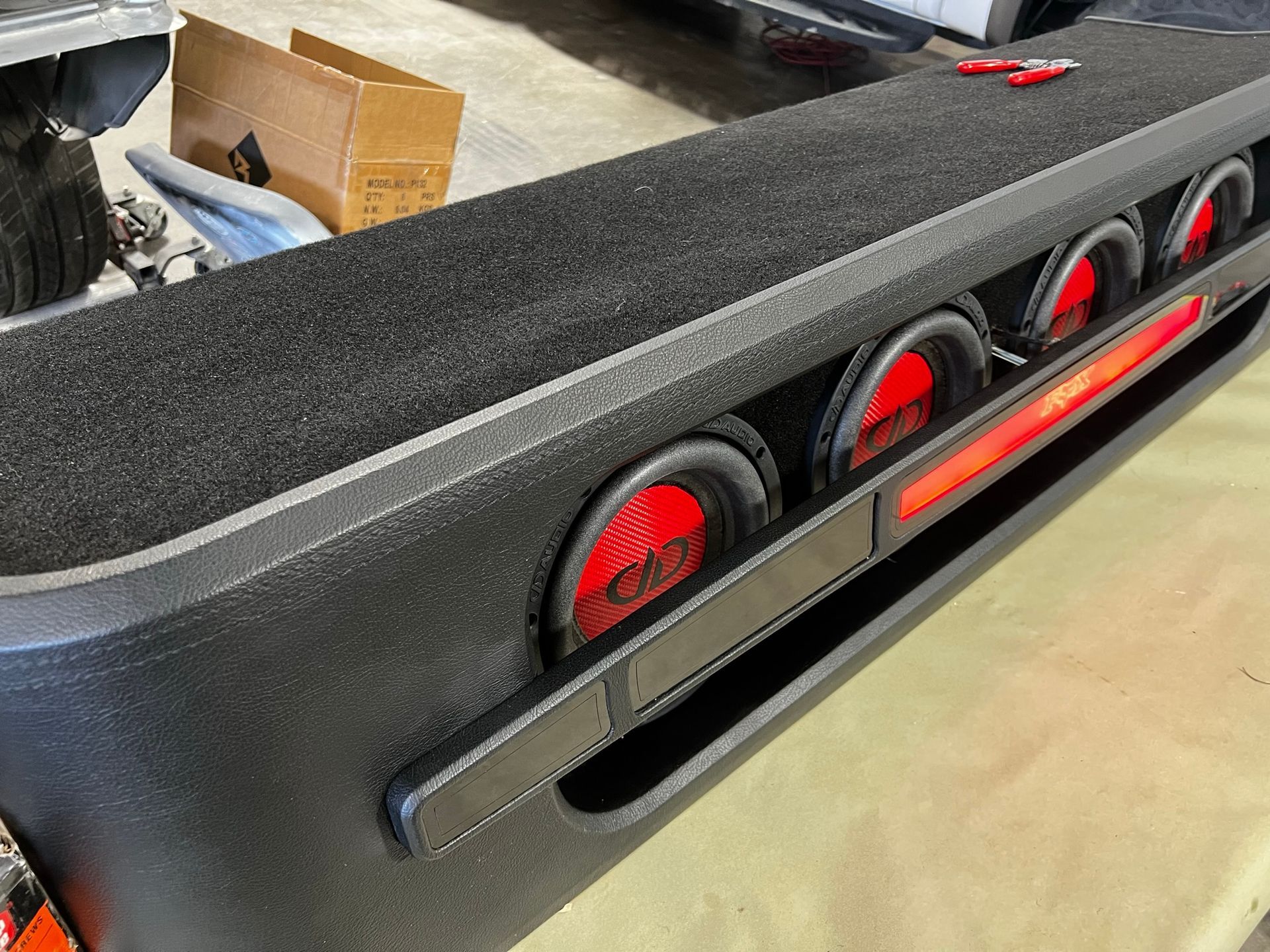 A subwoofer is sitting on top of a table next to a car.