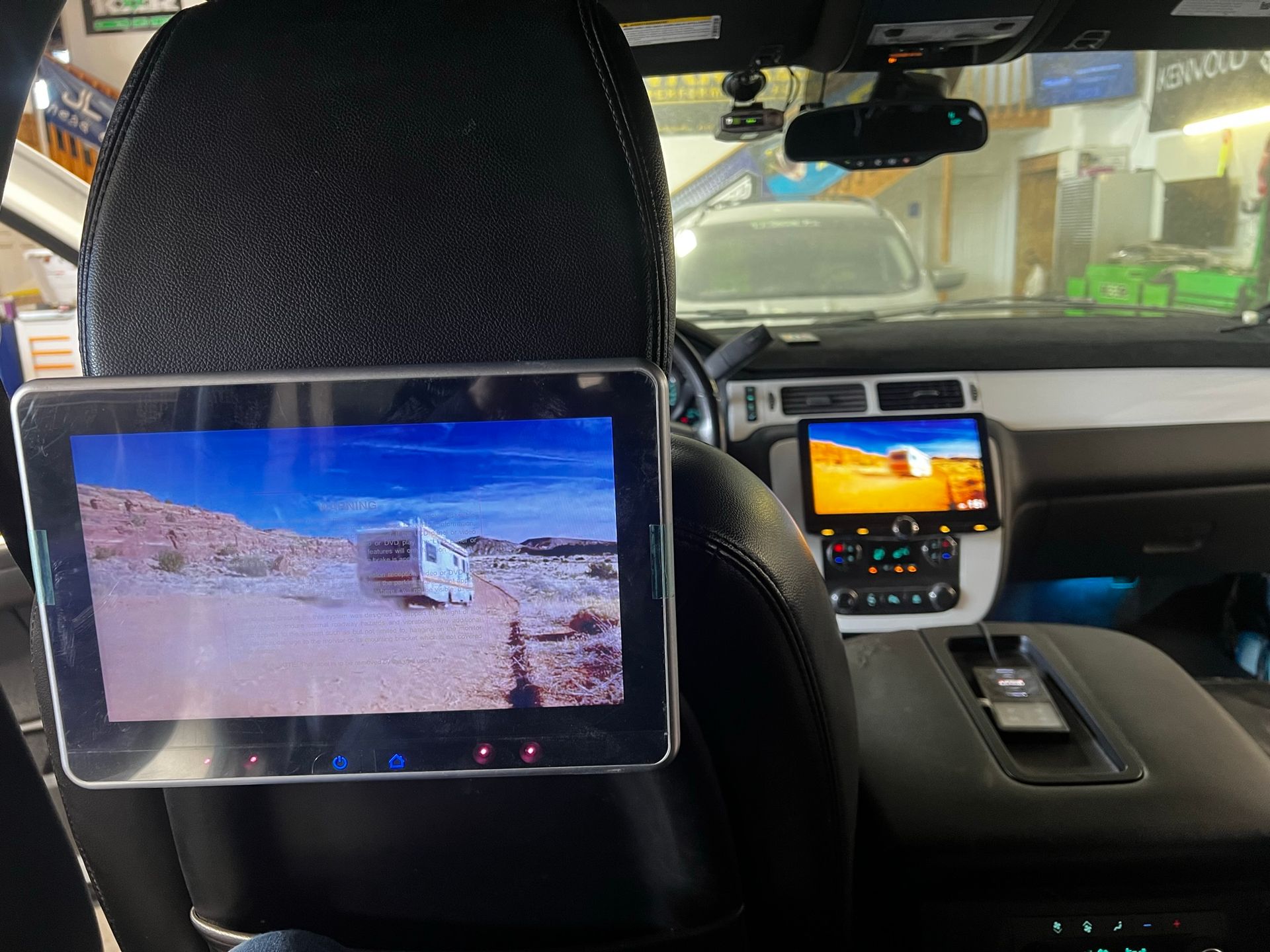 A tablet is attached to the headrest of a car.
