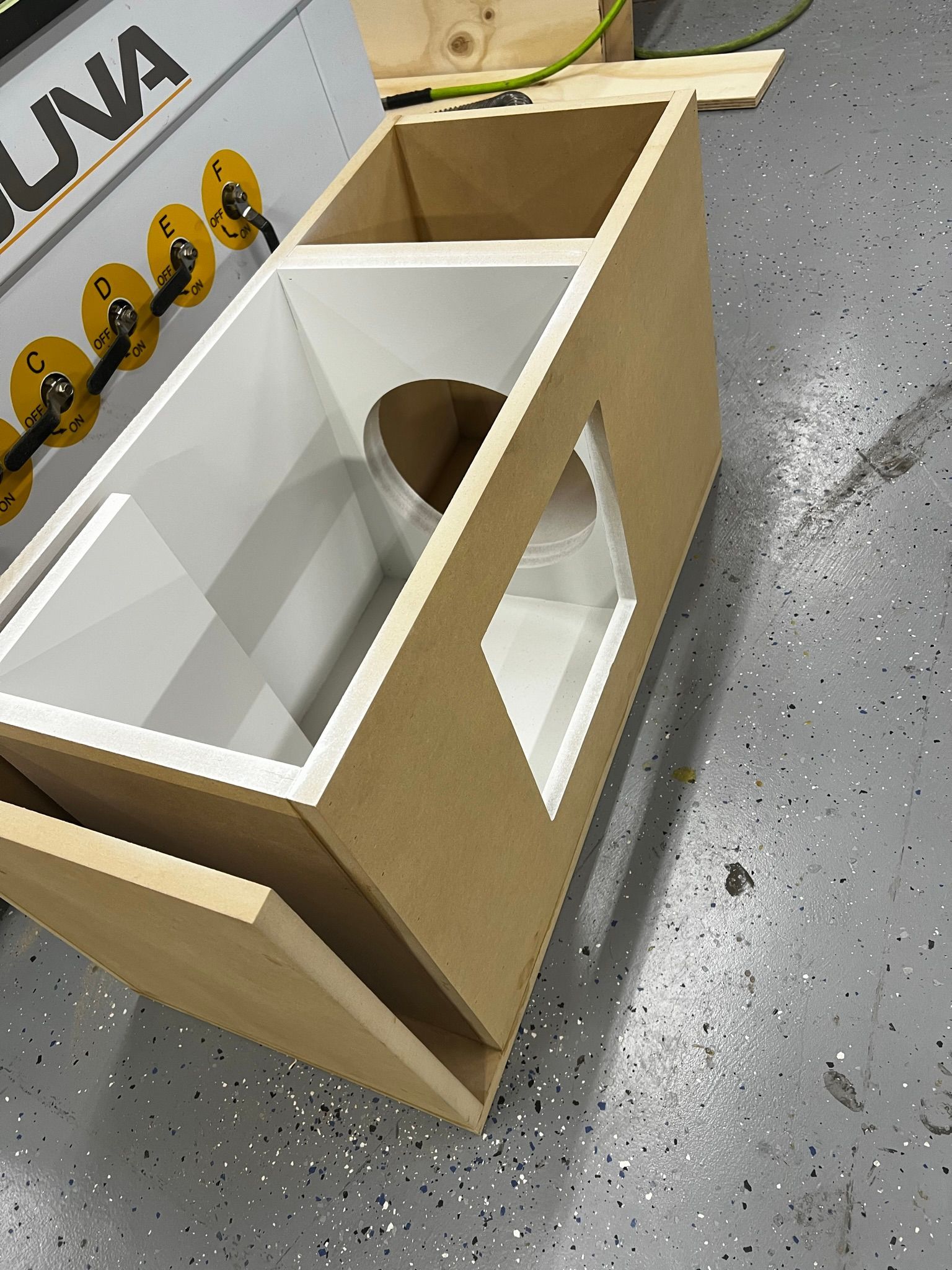 A wooden box is sitting on a concrete floor next to a machine.