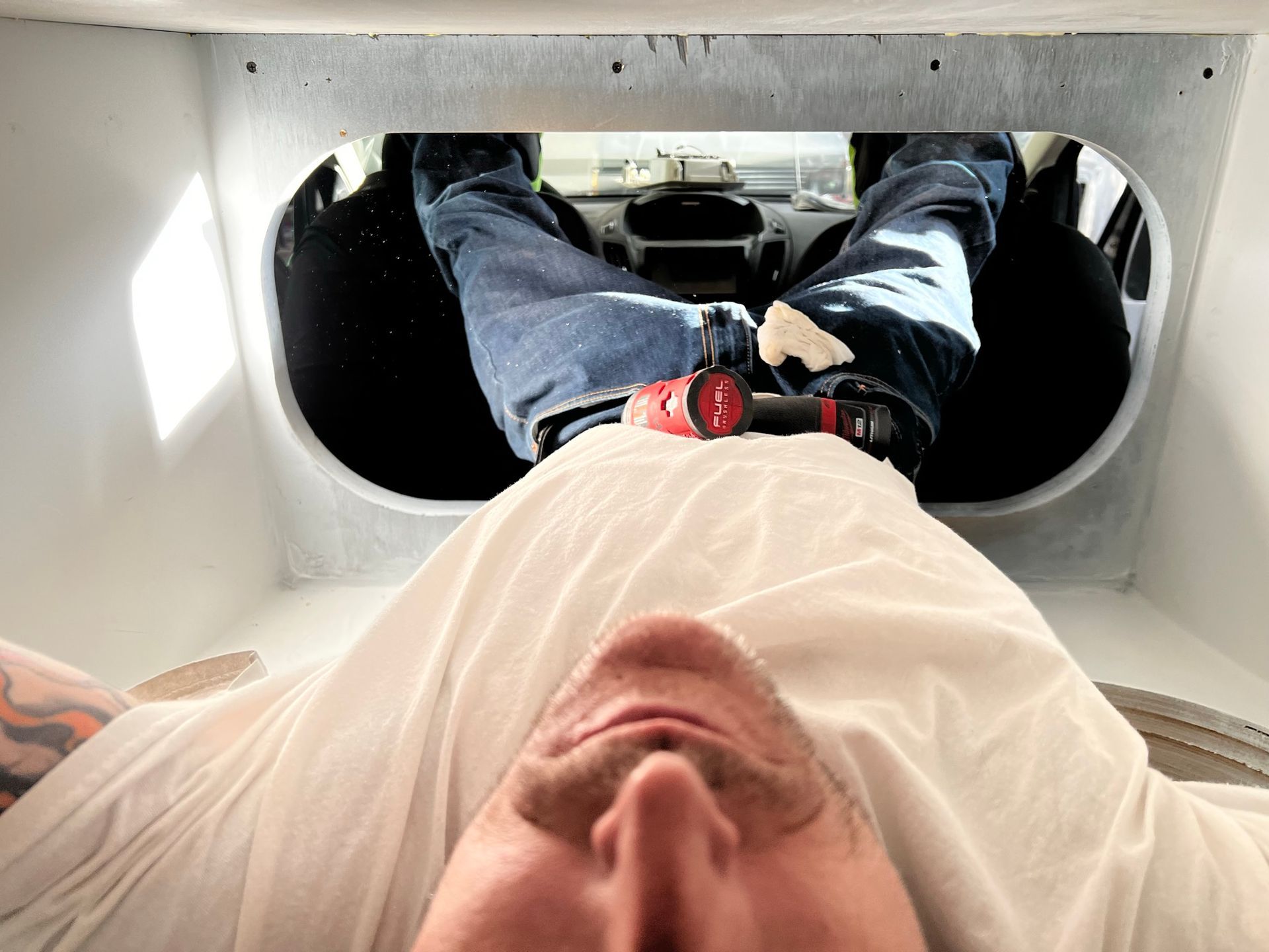 A man is laying down with his feet up in a hole.