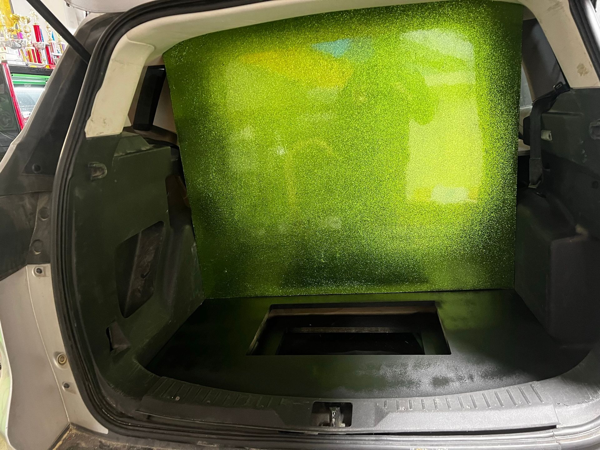 The trunk of a car is filled with green grass.