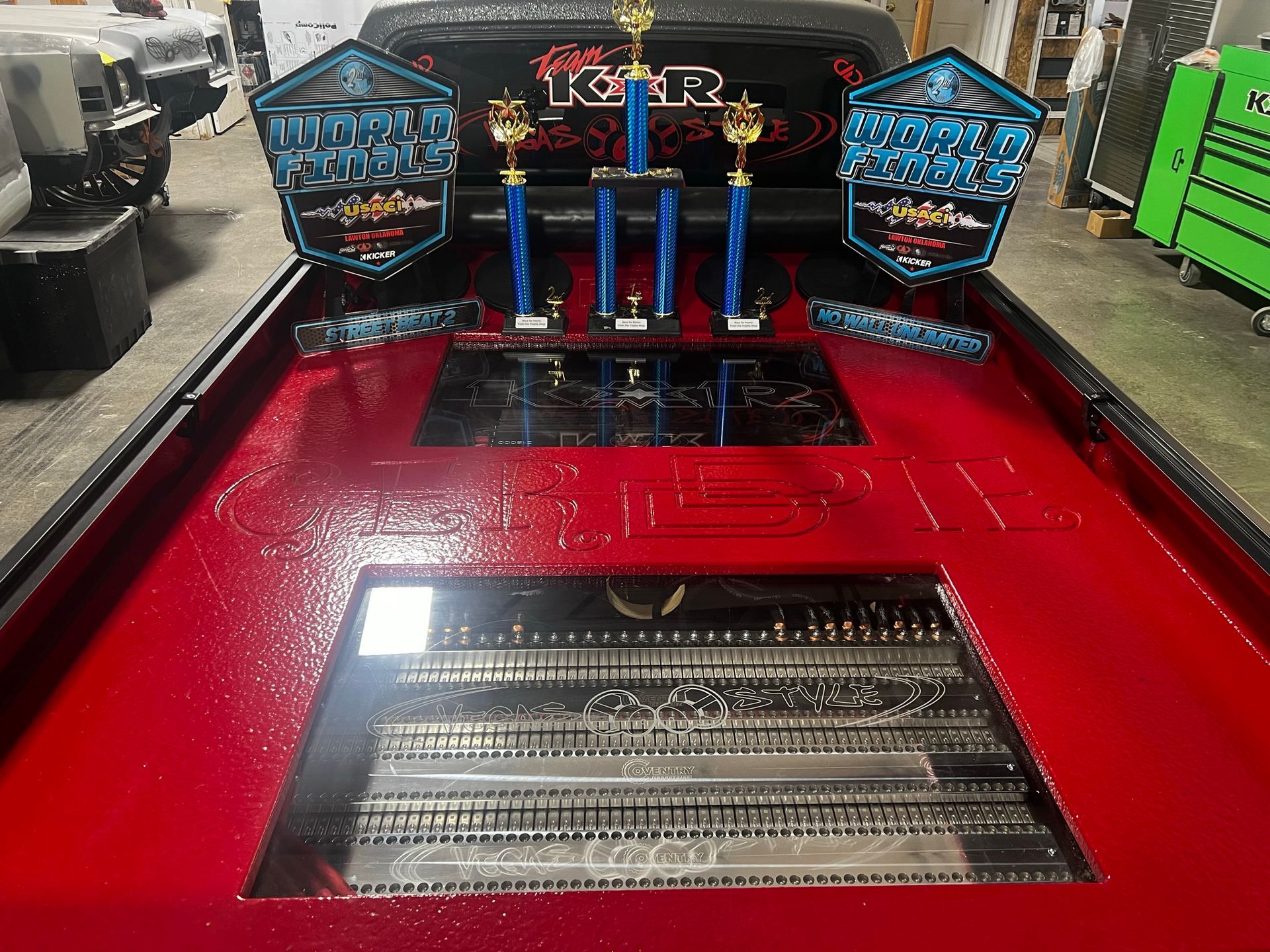 A red boat with three trophies on top of it