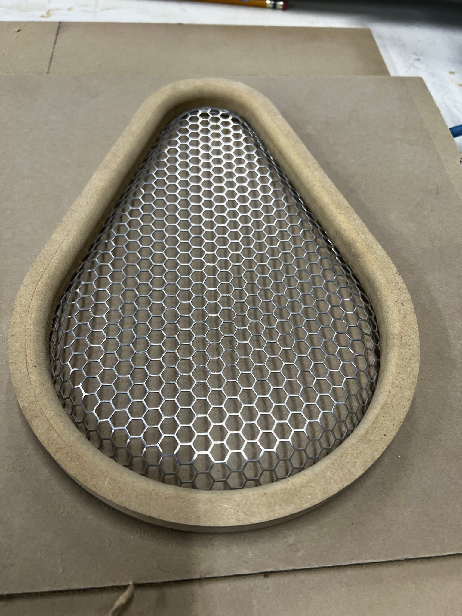 A piece of wire mesh is sitting on top of a piece of cardboard.