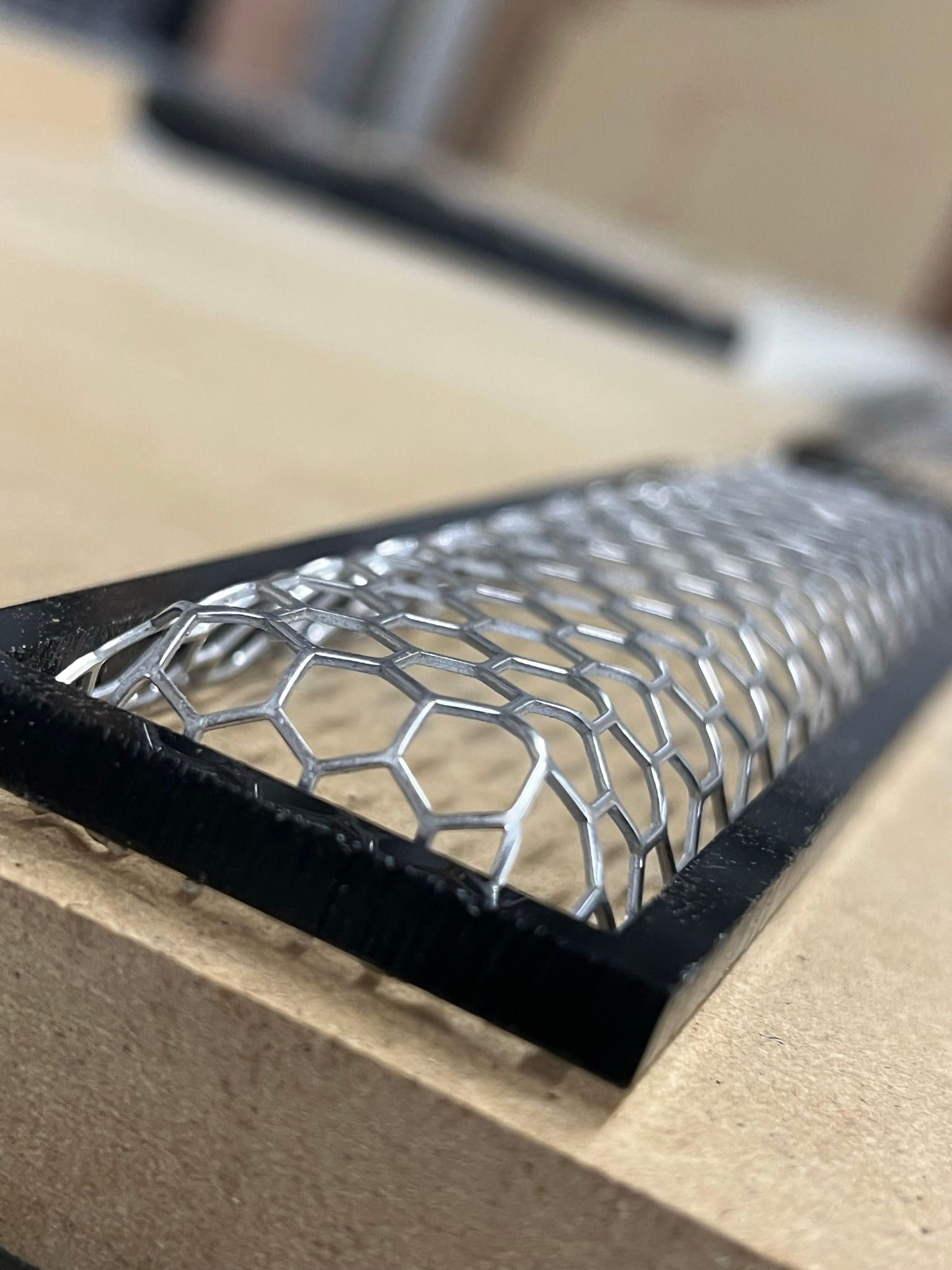 A close up of a metal mesh on a wooden surface.