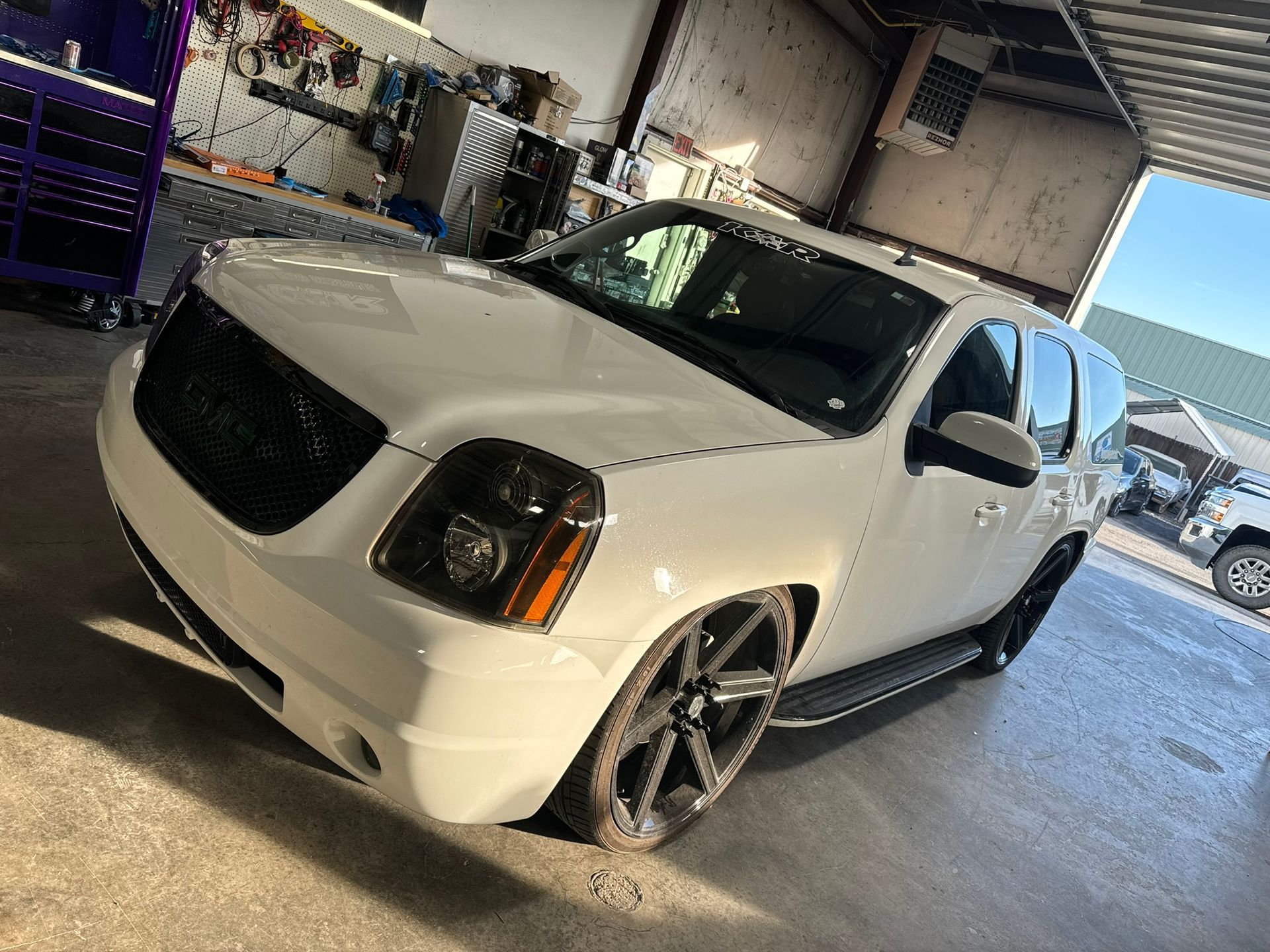 A white gmc yukon is parked in a garage.