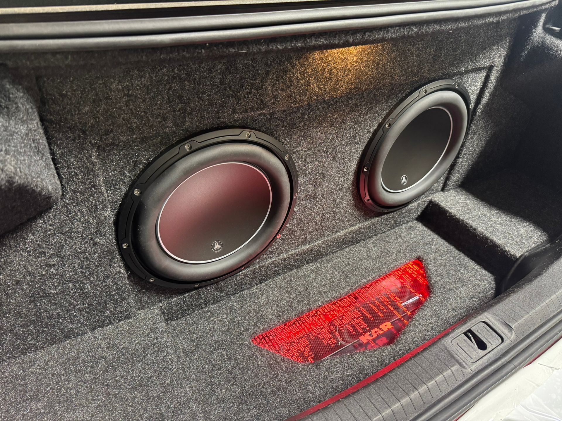 A subwoofer is sitting in the trunk of a car.