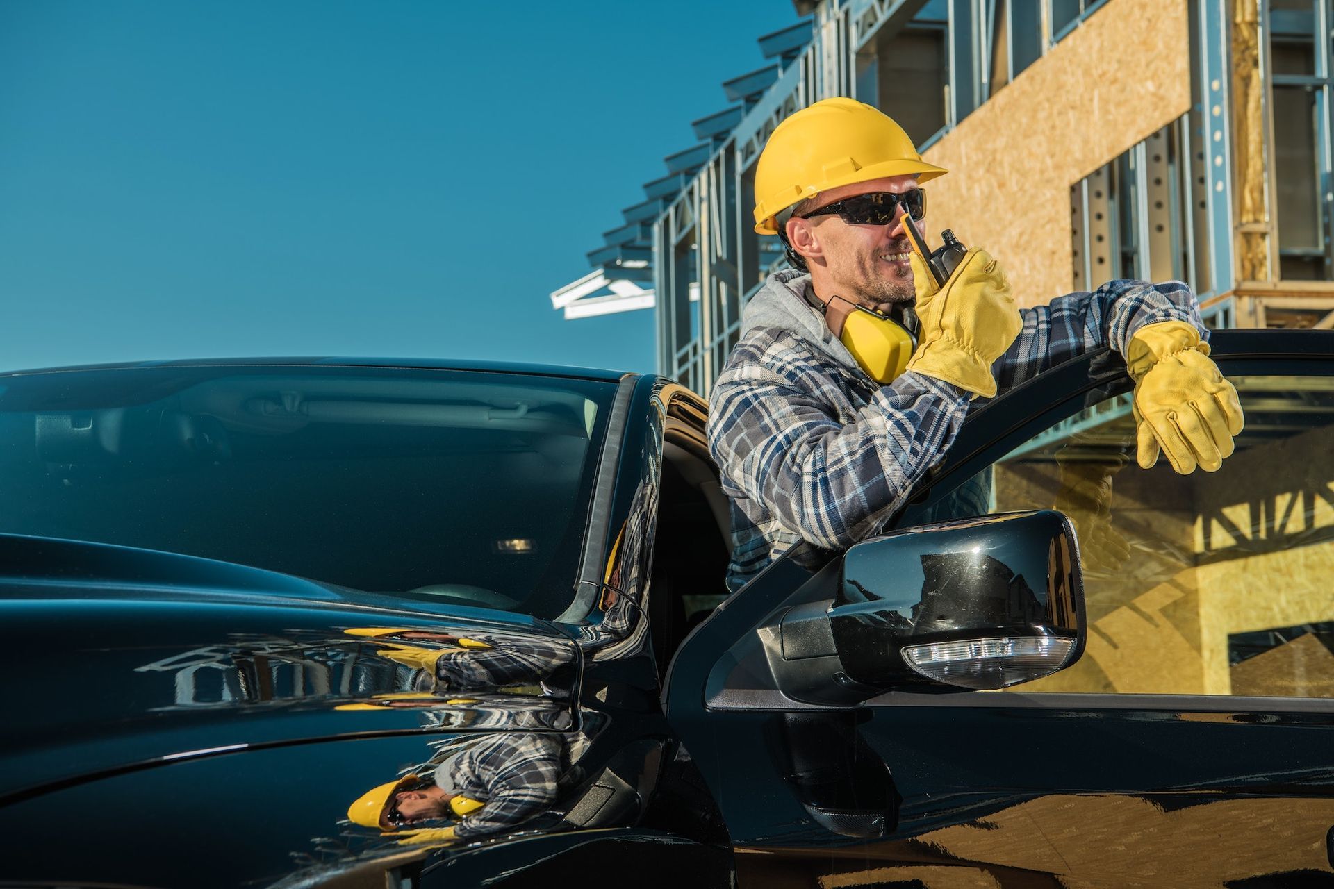 A construction worker is sitting in a truck talking on a walkie talkie.