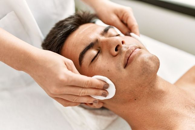 A man is getting a facial treatment at a spa.