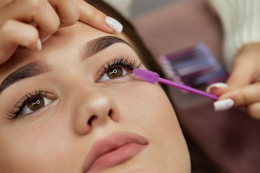 A woman is getting her eyelashes done by a makeup artist.