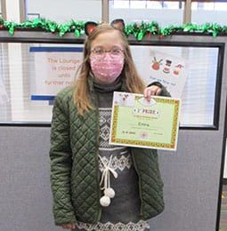 A young girl wearing a mask is holding a certificate.