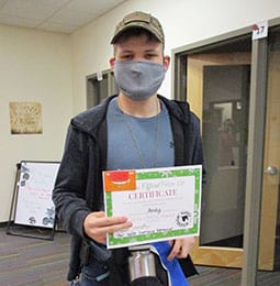 A young man wearing a mask is holding a certificate.