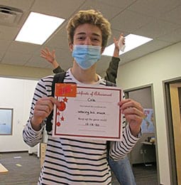 A young man wearing a mask is holding a certificate.