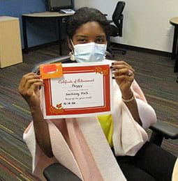 A woman wearing a mask is holding a certificate.