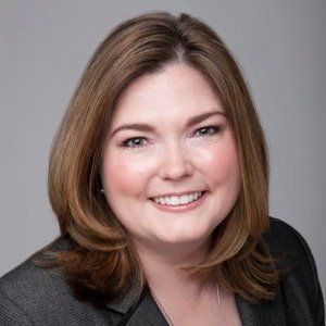 A woman in a suit is smiling for the camera.