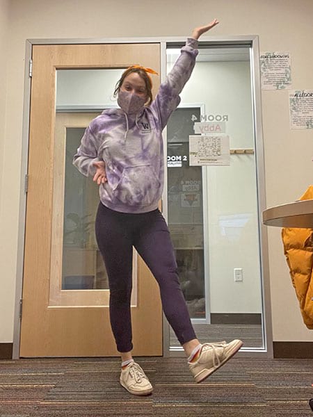 A woman wearing a mask is dancing in front of a door.