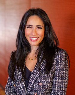 A woman with long brown hair is smiling for the camera