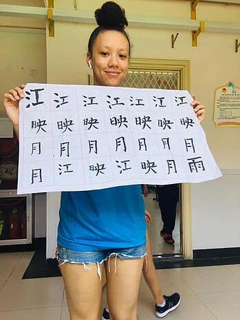 A woman is holding a piece of paper with chinese writing on it.