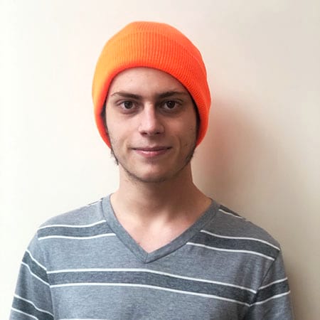 A young man wearing an orange beanie and a striped shirt