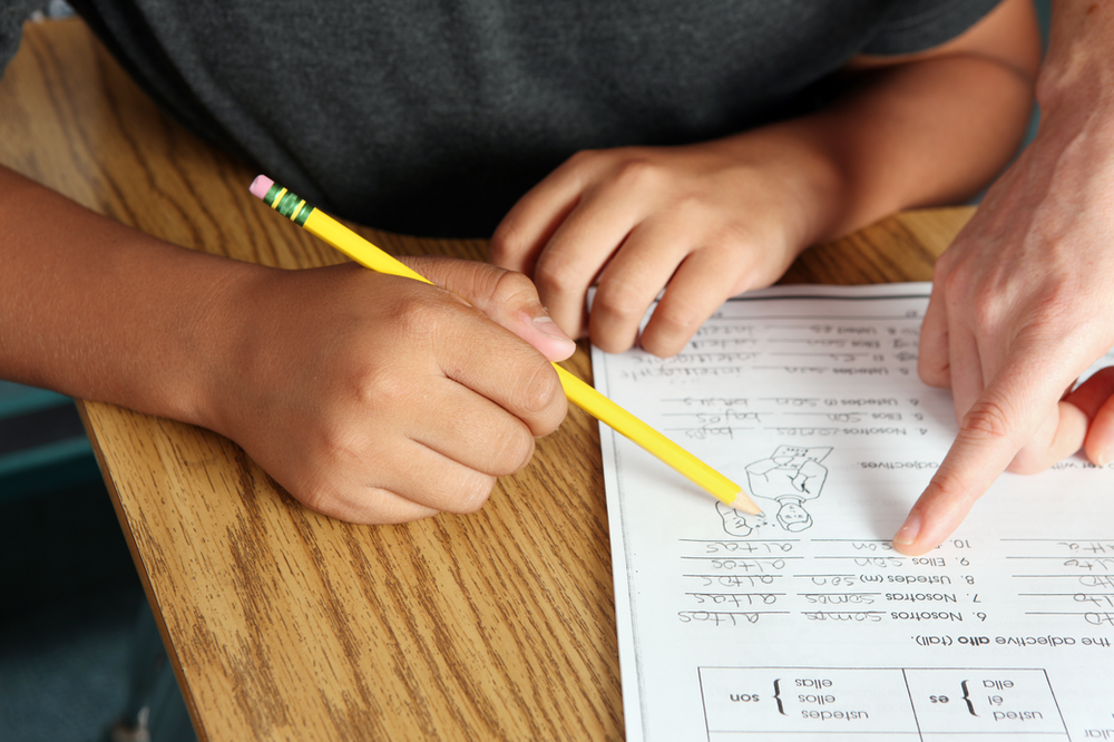 A person pointing at a piece of paper with a pencil on it