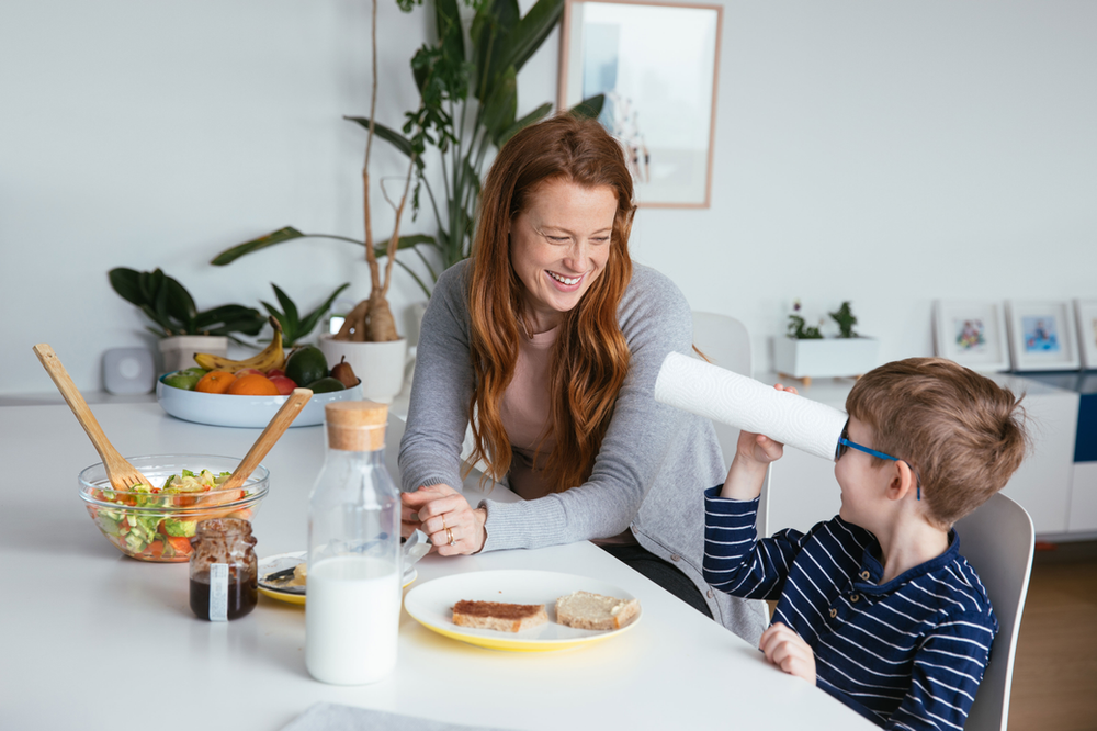 A woman and a boy are sitting at a table with a plate of food.