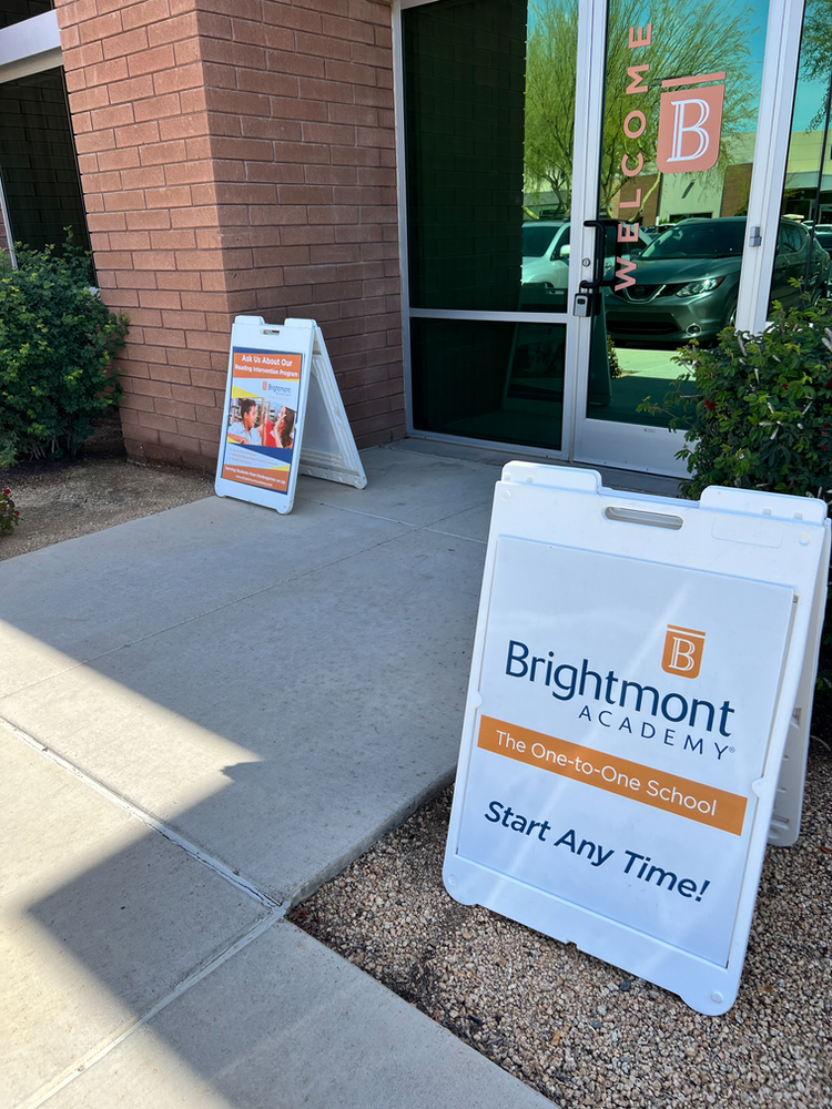 A sign for brightmont academy is on the sidewalk in front of a building.