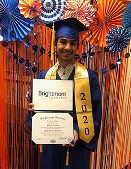 A man in a graduation cap and gown is holding a diploma.