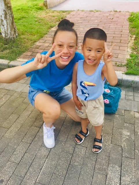 A woman and a little boy are posing for a picture on a sidewalk.