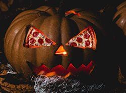 A pumpkin with a slice of pizza carved into it 's face.