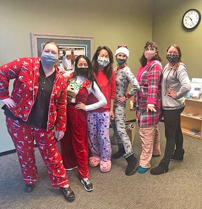 A group of women wearing pajamas and masks are standing next to each other in a room.