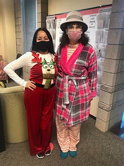 Two women wearing masks and pajamas are standing next to each other in a room.