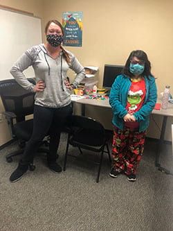 Two women wearing masks are standing next to each other in an office.