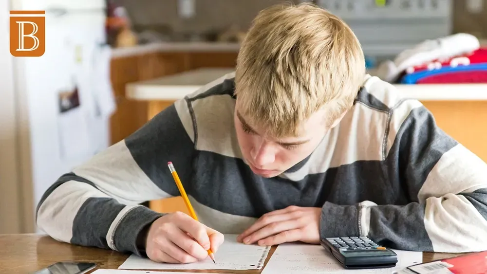 high school student writing at a desk