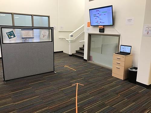 A room with a cubicle and a laptop on a desk.