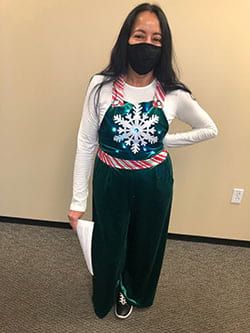 A woman wearing a mask and overalls is standing in a room.