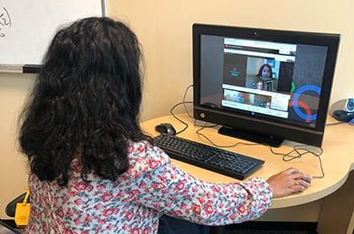 A woman is sitting at a desk using a computer.