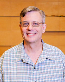 A man in a suit and tie is smiling for the camera